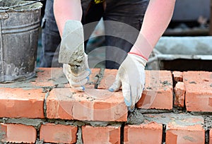 Bricklaying: builder building a brick masonry wall with brick trowel.  Masonry Wall Construction