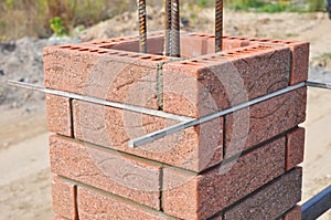 Bricklaying column from red brick blocks with metal rod