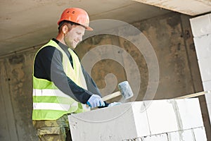 Bricklayer builder working with autoclaved aerated concrete blocks. Walling