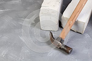 Silicate bricks, hammer on the gray concrete background. Copy space. Top view.