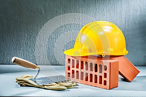 Bricks helmet gloves and trowel on concrette