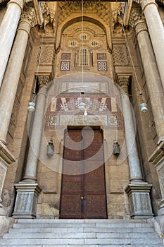 Bricks stone wall with arabesque decorated wooden door and marble engraved columns, al Refai Mosque