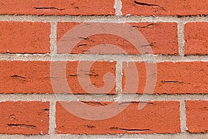 Brickwork rectangular red stones cracks with cement gray lines parallel row natural wall close-up grunge background
