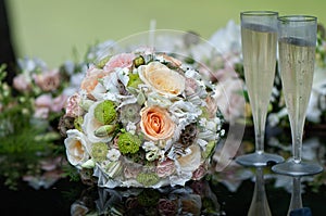 Bridal bouquet and champagne glasses on wedding car bonnet.