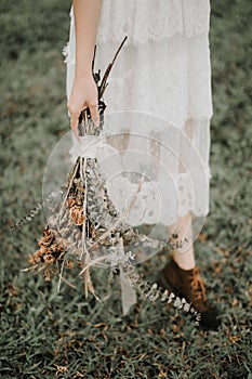 Bridal bouquet with dry flowers in a bride& x27;s hand; boho style wedding