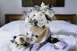 Bridal bouquet with fresh eucalyptus, peony and eustoma flowers posy with wedding shoes and floral hair decor on the bed