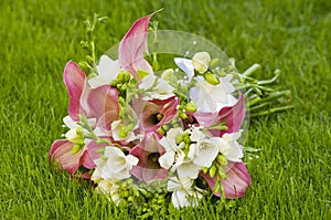 Bridal bouquet laying on green grass. Beautiful romantic white and magenta wedding flowers with copy space and blurred background