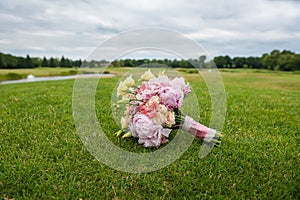 Bridal bouquet lies on a huge green lawn