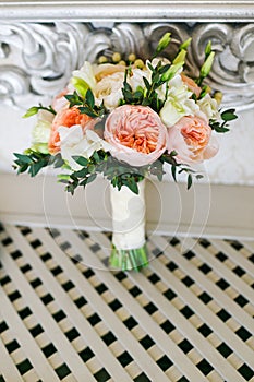 Bridal bouquet near the white vintage wall on the white wooden floor photo