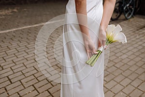 Bridal bouquet. Wedding. The slim woman in a white dress holds a beautiful bouquet of white flowers outdoors