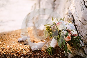 Bridal bouquet of white and pink roses, peonies, hortense branches of eucalypt tree, eustoma white ribbons and the shoes