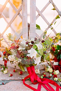 Bridal bouquet of white and red roses, little wild berries and red ribbons