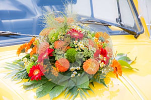 Bridal bouquet on a yellow wedding car