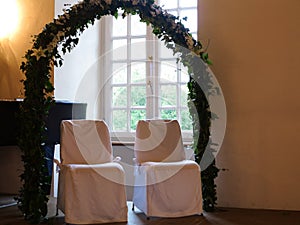 Bridal couple chairs under trellis arch at window and piano