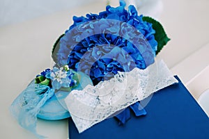 Bridal garter on a blue stand, with a blue hydrangeas on background. Wedding. Artwork