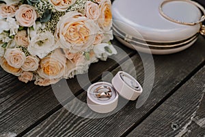 Bridal morning details composition. Top view of wedding rings, beautiful bouquet of pink flowers with ribbons, boutonniere and