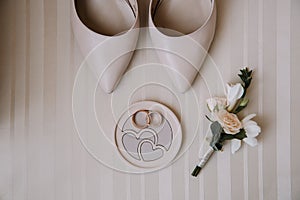 Bridal morning details composition. Top view of wedding rings, beautiful bouquet of pink flowers with ribbons, boutonniere and