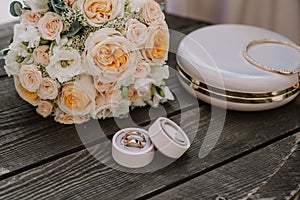 Bridal morning details composition. Top view of wedding rings, beautiful bouquet of pink flowers with ribbons, boutonniere and