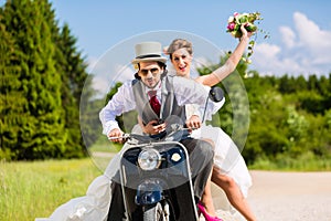 Bridal pair driving motor scooter wearing gown and suit