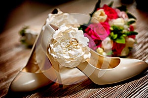 Bridal shoes and rings against wedding bouquet flowers