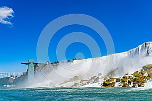 The Bridal Veil and American Falls cascade forcefully, mist rising above the Cave of the Winds lookout, Rainbow Bridge