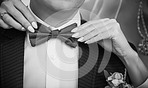 Bride adjusting the bowtie of the groom. Woman`s hands touch the tie of her betrothed, close up. Theme of the wedding, newlyweds,