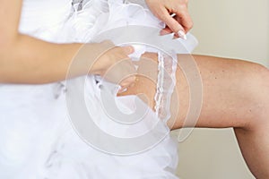 Bride is adjusting a garter on her leg
