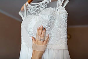 The bride adores wedding dress, white lace, bride`s hand with lace and manicure, morning bride