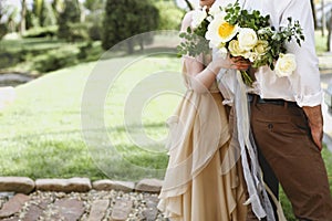 Bride with amazing bouquet of fresh delicate flowers and groom hugging