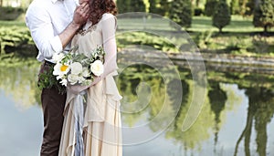 Bride with amazing bouquet of fresh delicate flowers and groom hugging