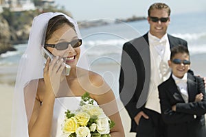 Bride Answering Mobilephone At Beach