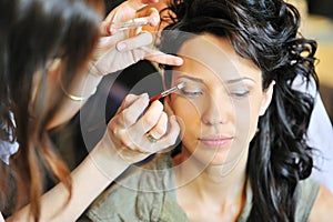 Bride applying wedding make-up by make-up artist photo