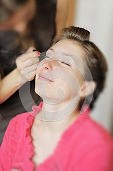 Bride applying wedding make-up by professional make-up artist