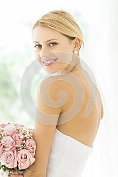 Bride In Backless Wedding Dress With Flower Bouquet Smiling photo