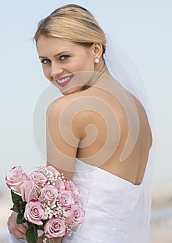 Bride In Backless Wedding Dress Holding Flower Bouquet Against S photo