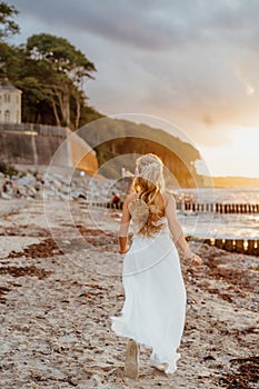 Bride on the beach. Young woman in white dress runs on the beach in sunlight