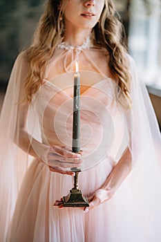 Bride in a beautiful dress with a burning candle in her hands