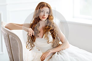 Bride in beautiful dress sitting resting on sofa indoors