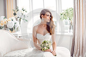 Bride in beautiful dress sitting resting on sofa indoors