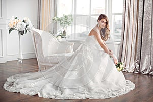 Bride in beautiful dress sitting resting on sofa indoors