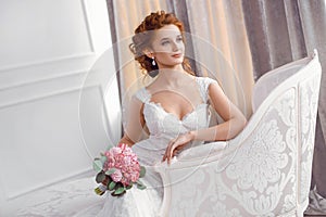 Bride in beautiful dress sitting resting on sofa indoors