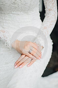 Bride in a beautiful lace white dress, close-up of hands with rings. Excitement before wedding.