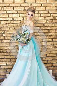 Bride in a beautiful turquoise dress in anticipation of wedding. Blonde in lace dress sea green with a bouquet . Happy bride