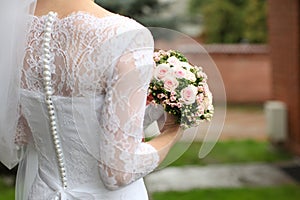 Bride in a beautiful white wedding dress with lace and pearls, s