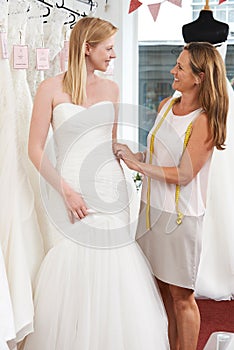 Bride Being Fitted For Wedding Dress By Store Owner photo