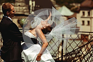 Bride bends over in groom`s hands and her veil spreads around