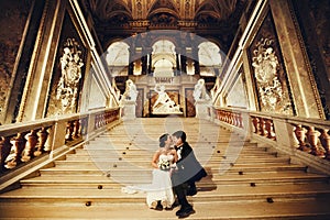 Bride bites groom`s nose sitting on the marble stairs in the the