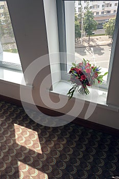 Bride bouquet of red roses before the wedding stands on the window overlooking the street of the city