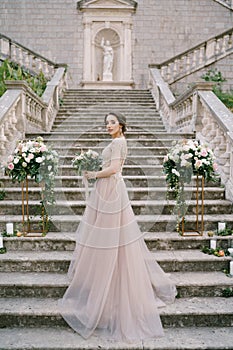 Bride with a bouquet on the stone steps of an ancient villa