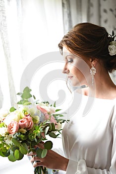 Bride with a bouquet waiting for the groom near the window